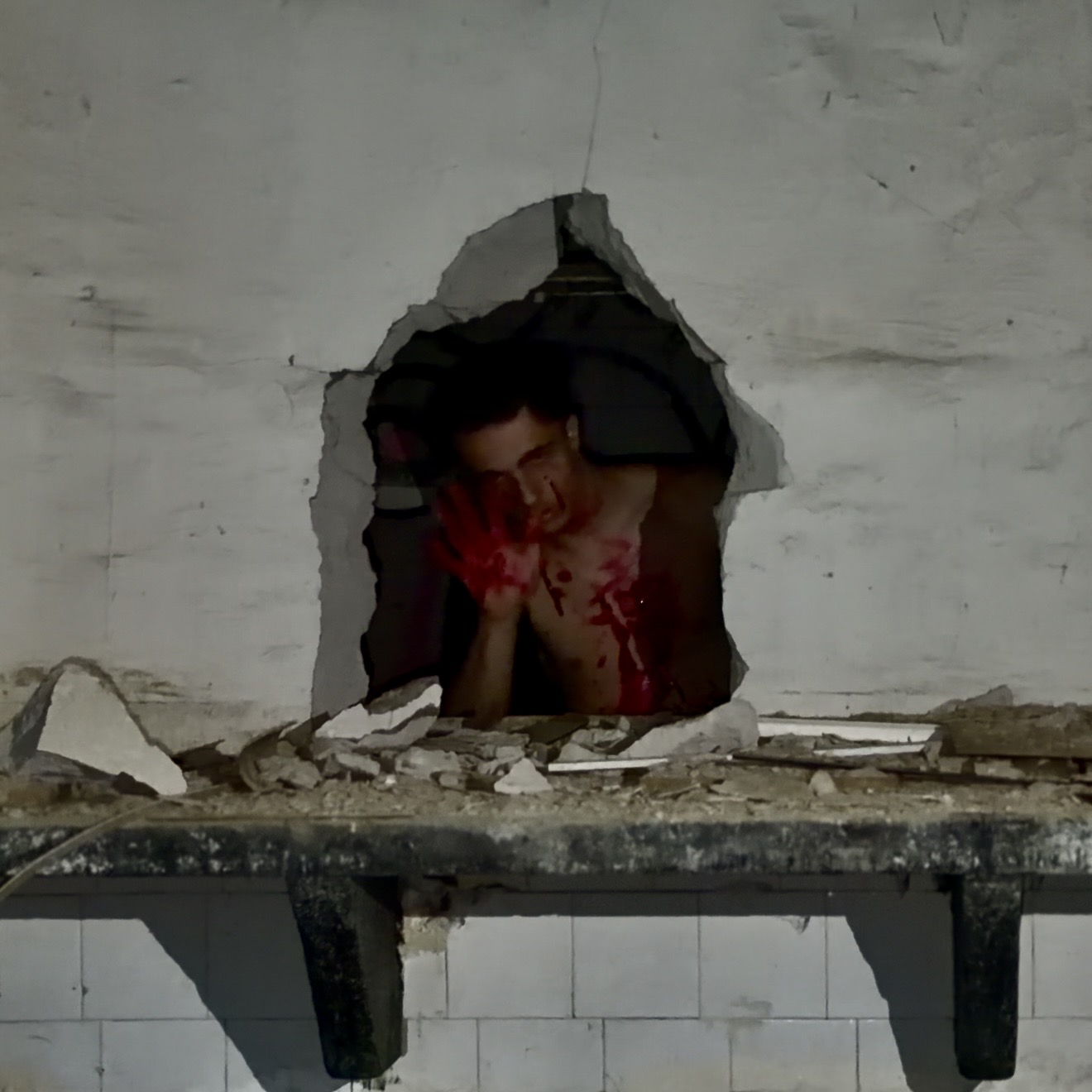 Album cover for Desire Over the Spirit: a bloodied figure framed inside a hole punched through a concrete wall